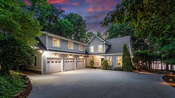 A two-story house with a covered garage, surrounded by trees and a well-maintained lawn.