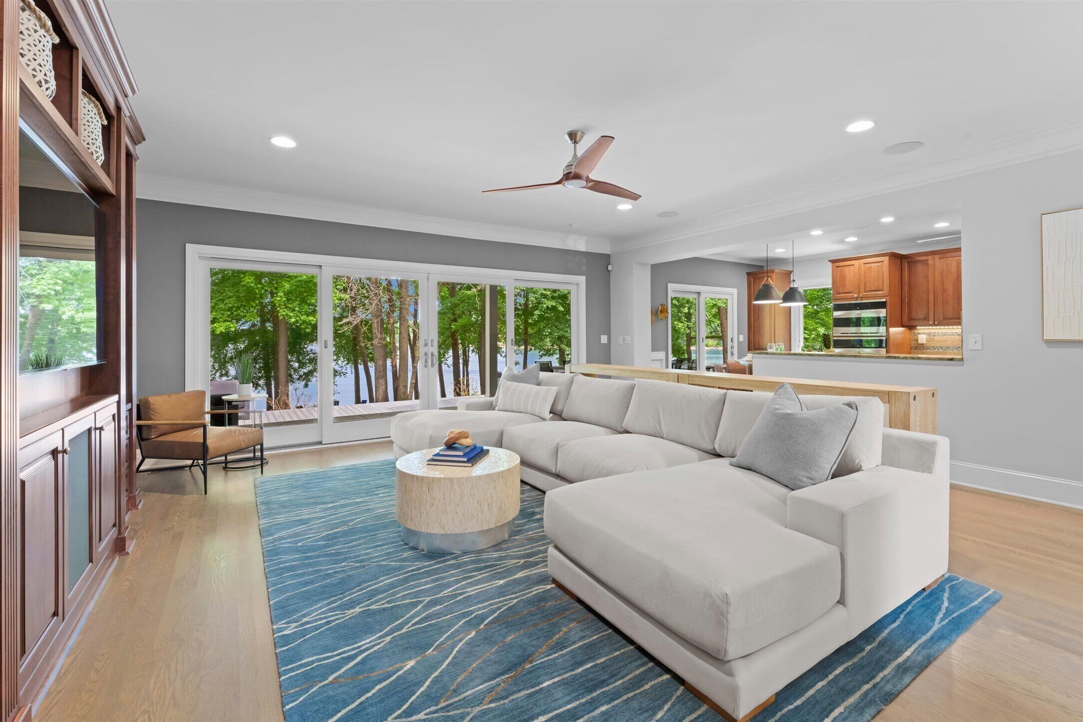 A modern living room with a sectional sofa, a round coffee table, and a ceiling fan.