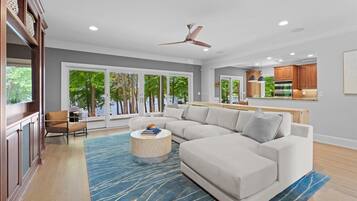 A modern living room with a sectional sofa, a round coffee table, and a ceiling fan.