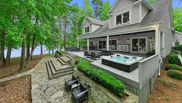 Ein zweistöckiges Haus mit Terrasse, Sitzgelegenheiten im Freien und einem Whirlpool.