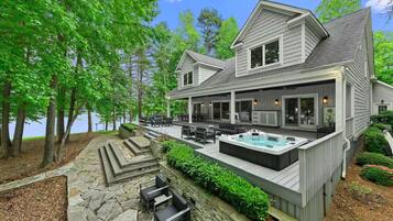 A two-story house with a deck, outdoor seating, and a hot tub.