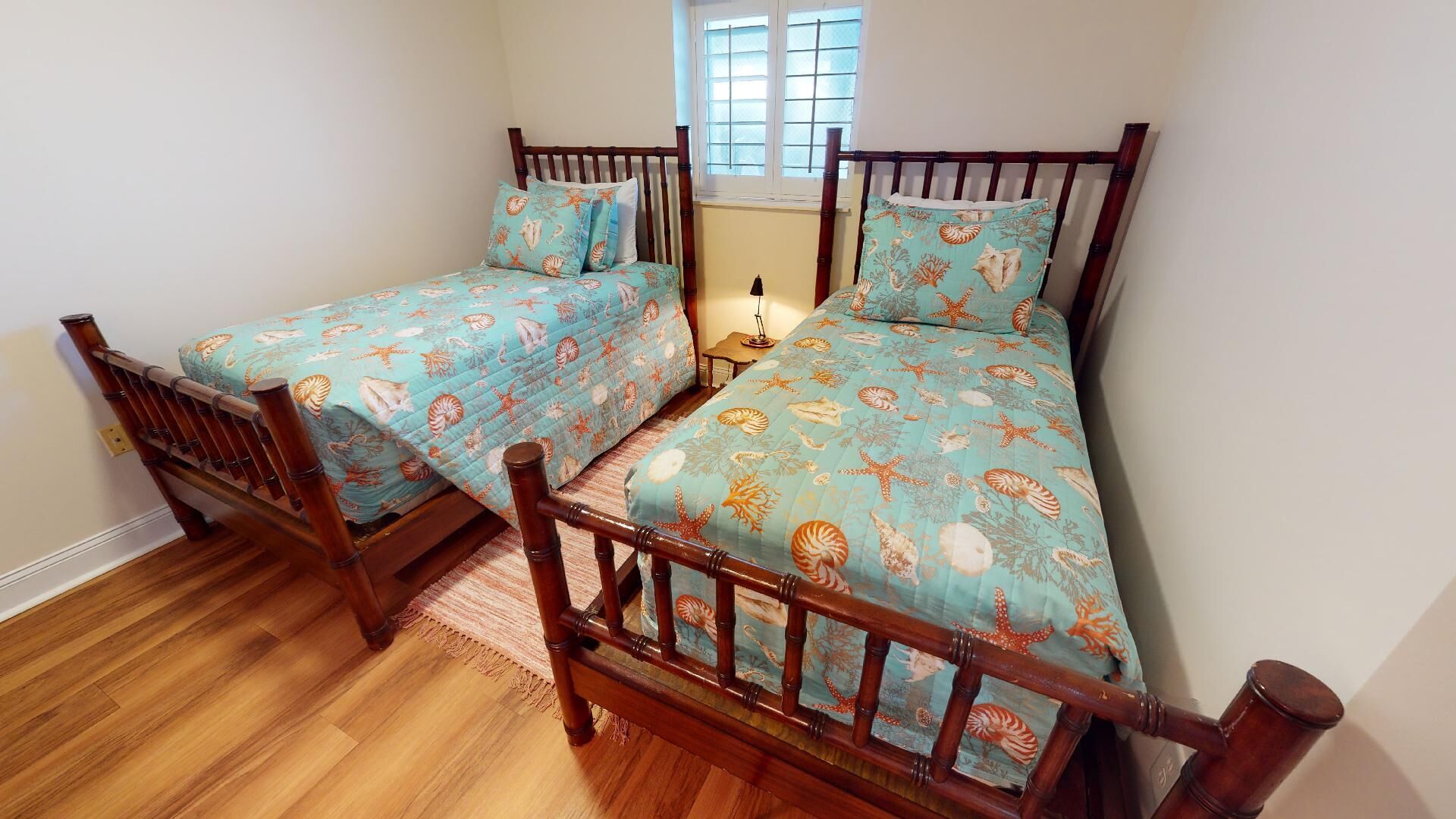 A room with two wooden beds, each with a blue bedspread featuring a sea-themed pattern.