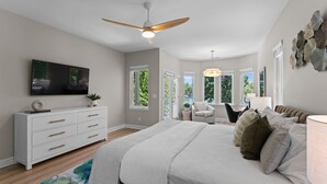 A bedroom with a bed, a TV, a ceiling fan, and a window. - Waddell Waters (Mooresville)