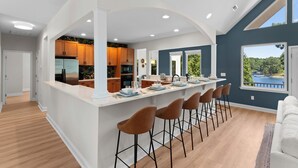 A modern kitchen with a central island, wooden cabinets, and a view of a lake. - Waddell Waters (Mooresville)