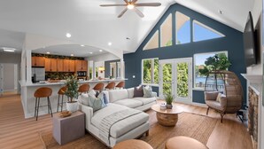 A spacious living room with a large L-shaped sofa, a coffee table, and a dining area with bar stools. - Waddell Waters (Mooresville)