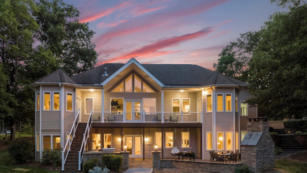 A two-story house with a covered patio, a stone fireplace, and a staircase leading to the upper level. - Waddell Waters (Mooresville)
