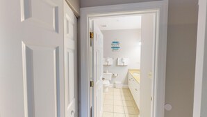 Een smalle gang die leidt naar een badkamer met toilet, wastafel en handdoekrek.