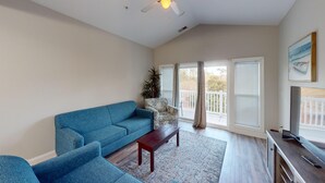 A spacious living room with a blue sofa, a wooden coffee table, and a TV on a wooden cabinet. - World Tour 1009-301 (Myrtle Beach)
