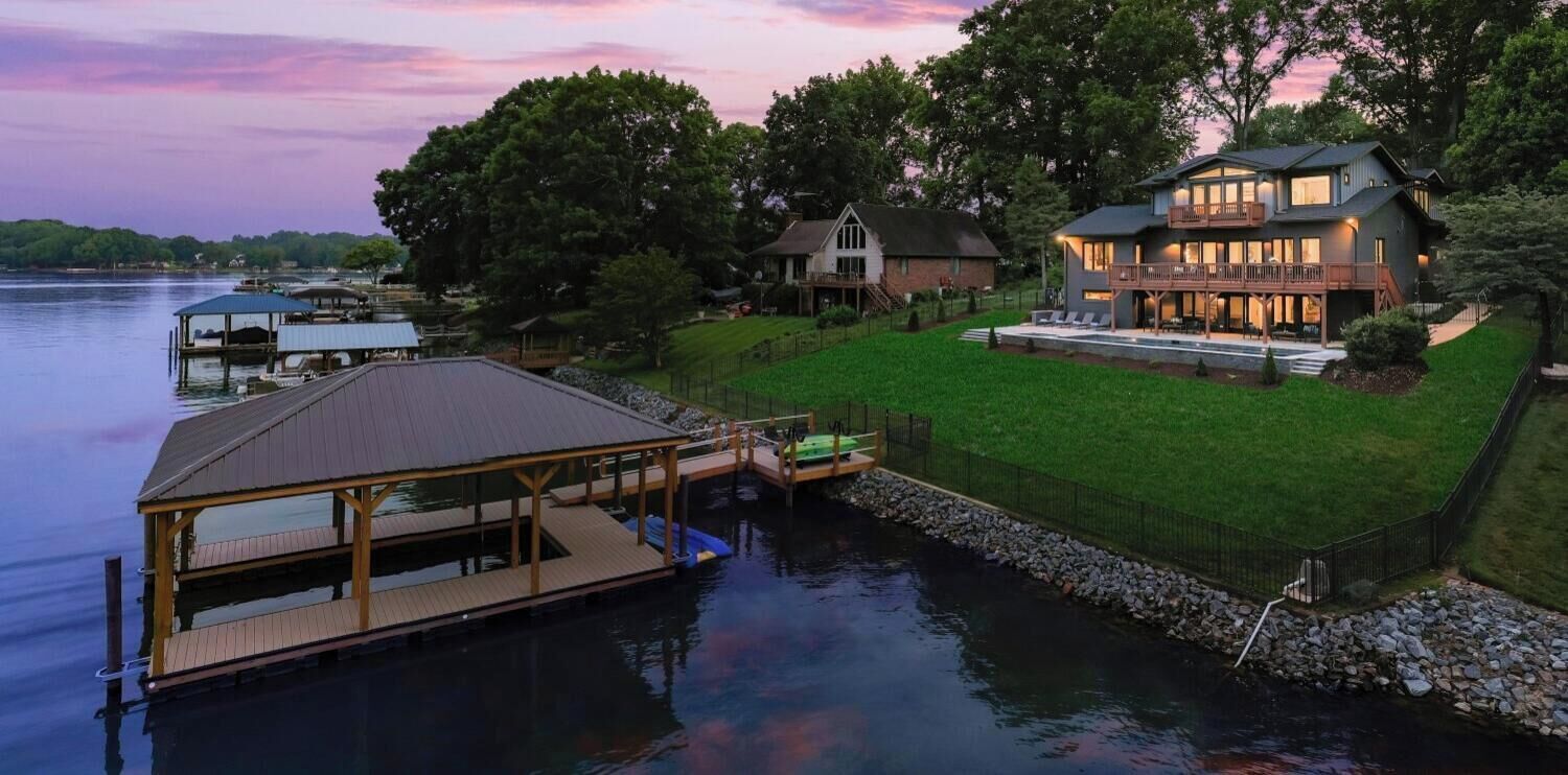 A lakeside property with a dock, a large house with a balcony, and a smaller building.