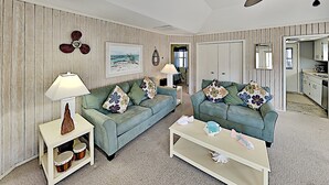 Ett vardagsrum med två soffor, ett soffbord, en lampa och en väggmonterad fläkt.