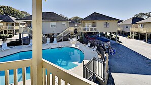 Ett bostadsområde med en swimmingpool, flera hus och en täckt utomhusplats med sittmöbler.