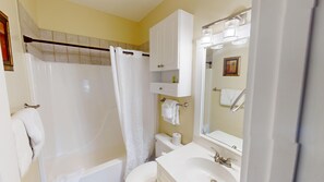 Ein Badezimmer mit Badewanne, Toilette, Waschbecken und Spiegel.