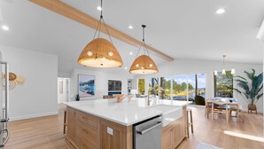 A modern kitchen with a large island, wooden cabinets, and pendant lighting. - Blanca Bay on Brawley (Mooresville)