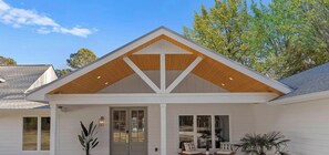 A modern house with a symmetrical facade, a central entrance with a glass door, and a covered porch area with two chairs. - Blanca Bay on Brawley (Mooresville)