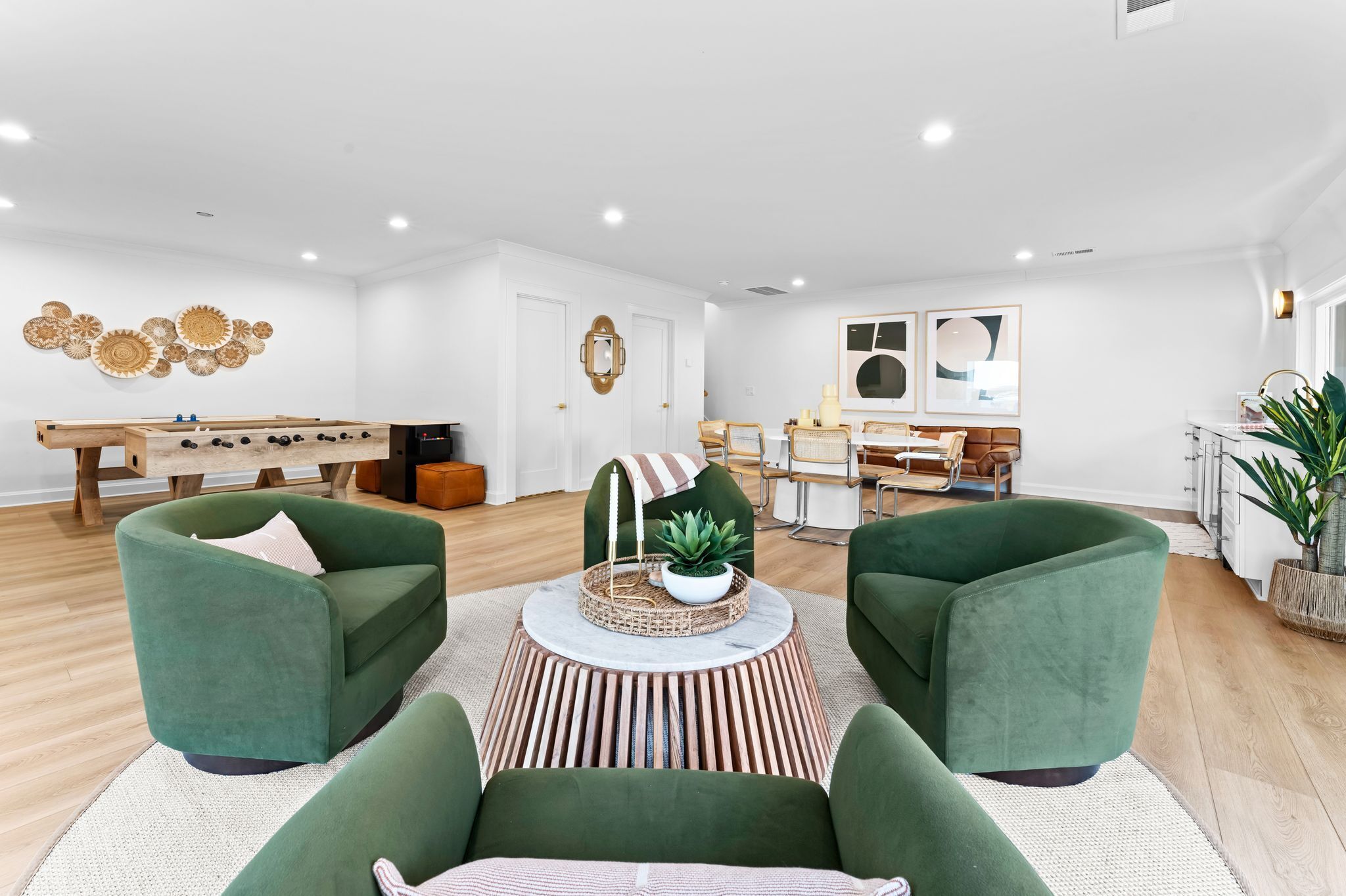 Una sala de estar moderna con sofás verdes, una mesa de centro y una zona de comedor con una mesa y sillas de madera.