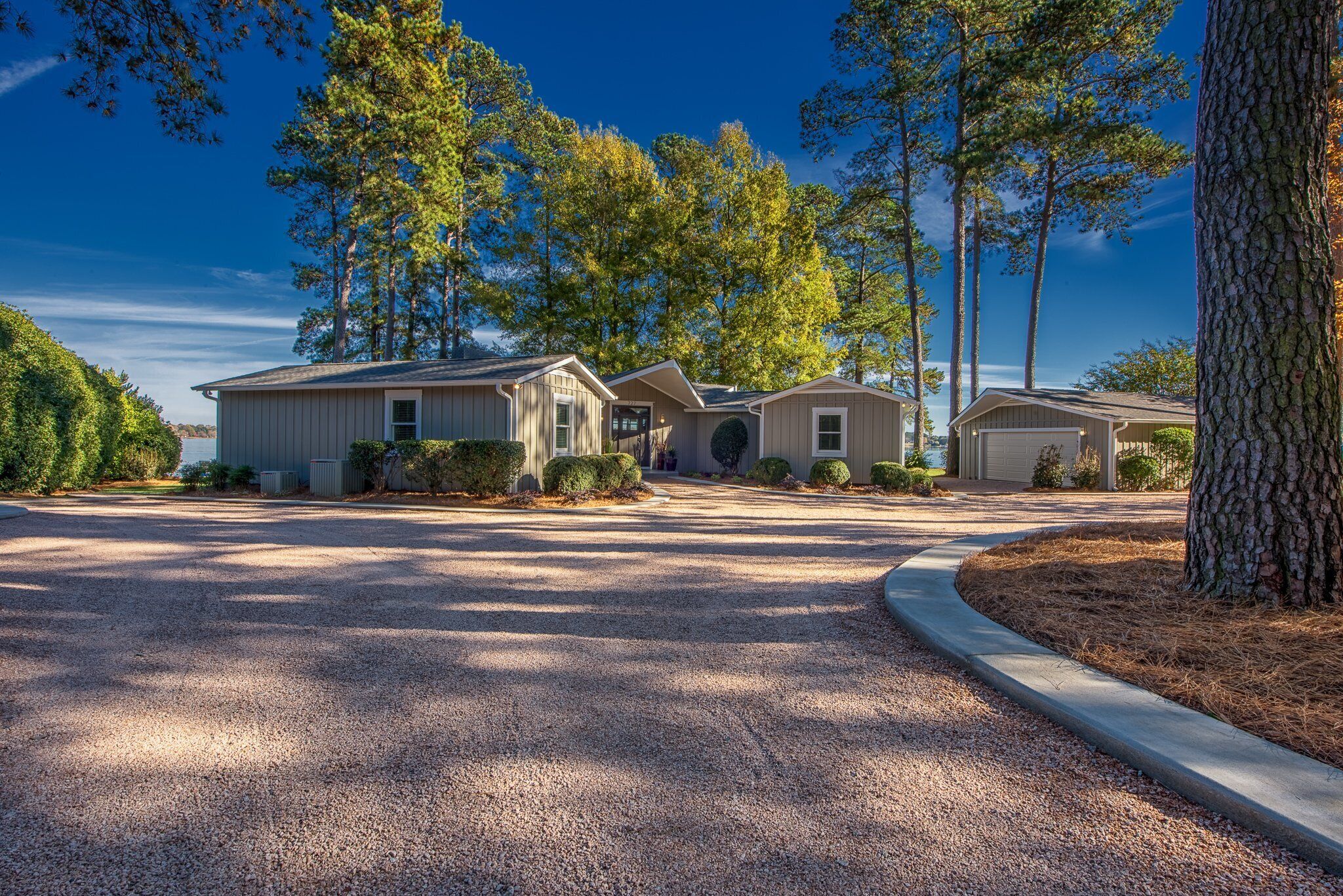 A residential property with a gravel driveway, a garage, and a house with a front porch.
