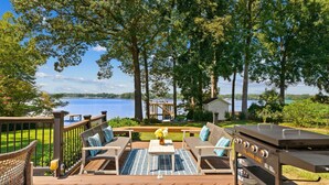 Une terrasse dotée de mobilier d’extérieur, d’un barbecue et offrant une vue sur un lac.