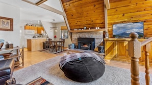 Un salon chaleureux avec une cheminée, un plafond en bois et un téléviseur.