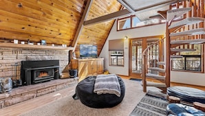Un intérieur de chalet chaleureux avec une cheminée, un coin salon confortable et un escalier en colimaçon.