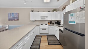 A modern kitchen with white cabinets, a stainless steel refrigerator, a microwave, and a gas stove. - Magnolia North 4881-204 (Myrtle Beach)