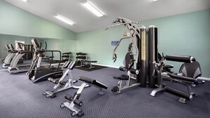 A gym with various exercise machines, a mirrored wall, and a carpeted floor. - Magnolia North 4881-204 (Myrtle Beach)