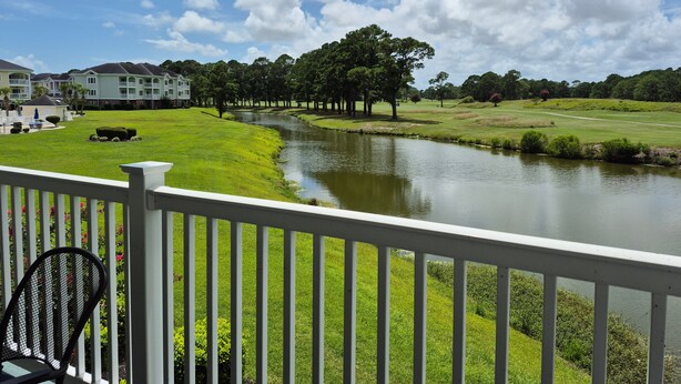 A view of a golf course with a pond, surrounded by well-maintained lawns and trees. - Magnolia North 4881-204 (Myrtle Beach)