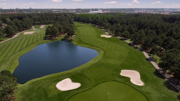 An aerial view of a golf course with a large lake, sand bunkers, and dense trees. - Magnolia Pointe Luster Leaf 4837-302 (Myrtle Beach)