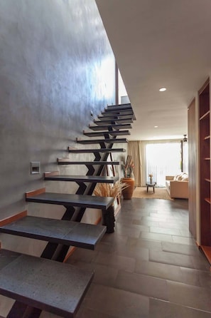 Ein modernes Interieur mit einem einzigartigen Treibwerdesign, einem Wohnbereich mit einer Couch und einem großen Fenster, das natürliches Licht hereinlässt.