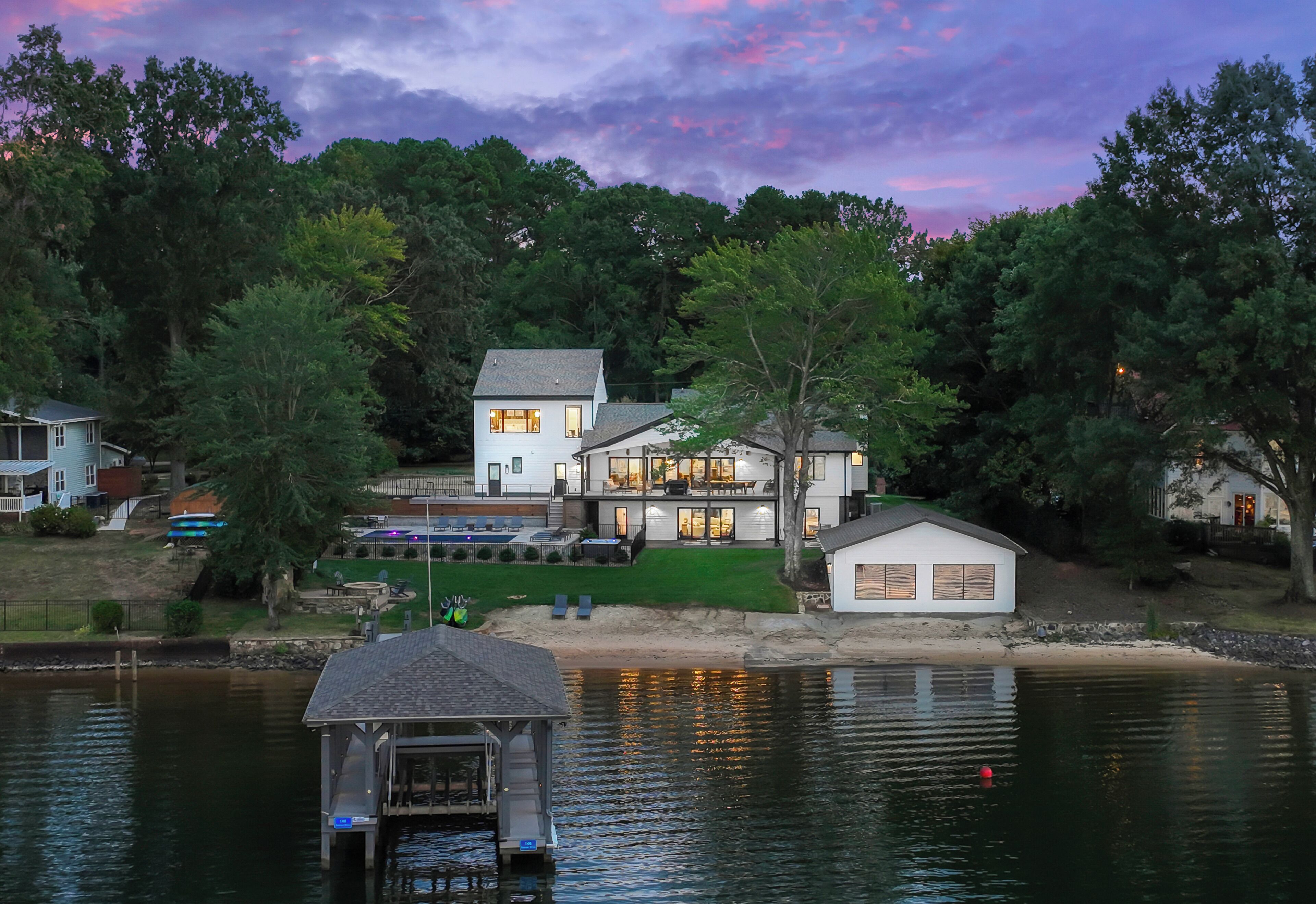 A lakeside house with a dock, a covered boat launch, and a well-maintained lawn.