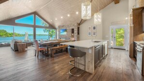 A spacious kitchen with a large island, wooden flooring, and a view of the lake. - Lake Norman Hideaway (Mooresville)
