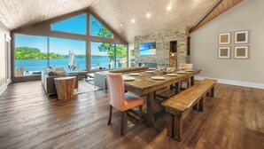 A spacious dining area with a large wooden table, benches, and a stone accent wall. - Lake Norman Hideaway (Mooresville)