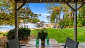 Une terrasse couverte, dotée d’une table et de chaises, qui offre une vue sur un lac et une zone abritant des quais.