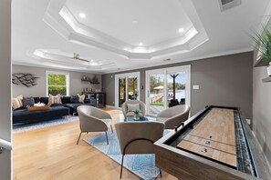 Un salon spacieux avec une table de billard, des sièges confortables et une vue sur l’extérieur.