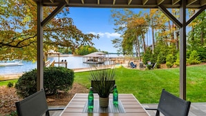 A covered patio with a table and chairs, a view of a lake, and a gazebo in the background.