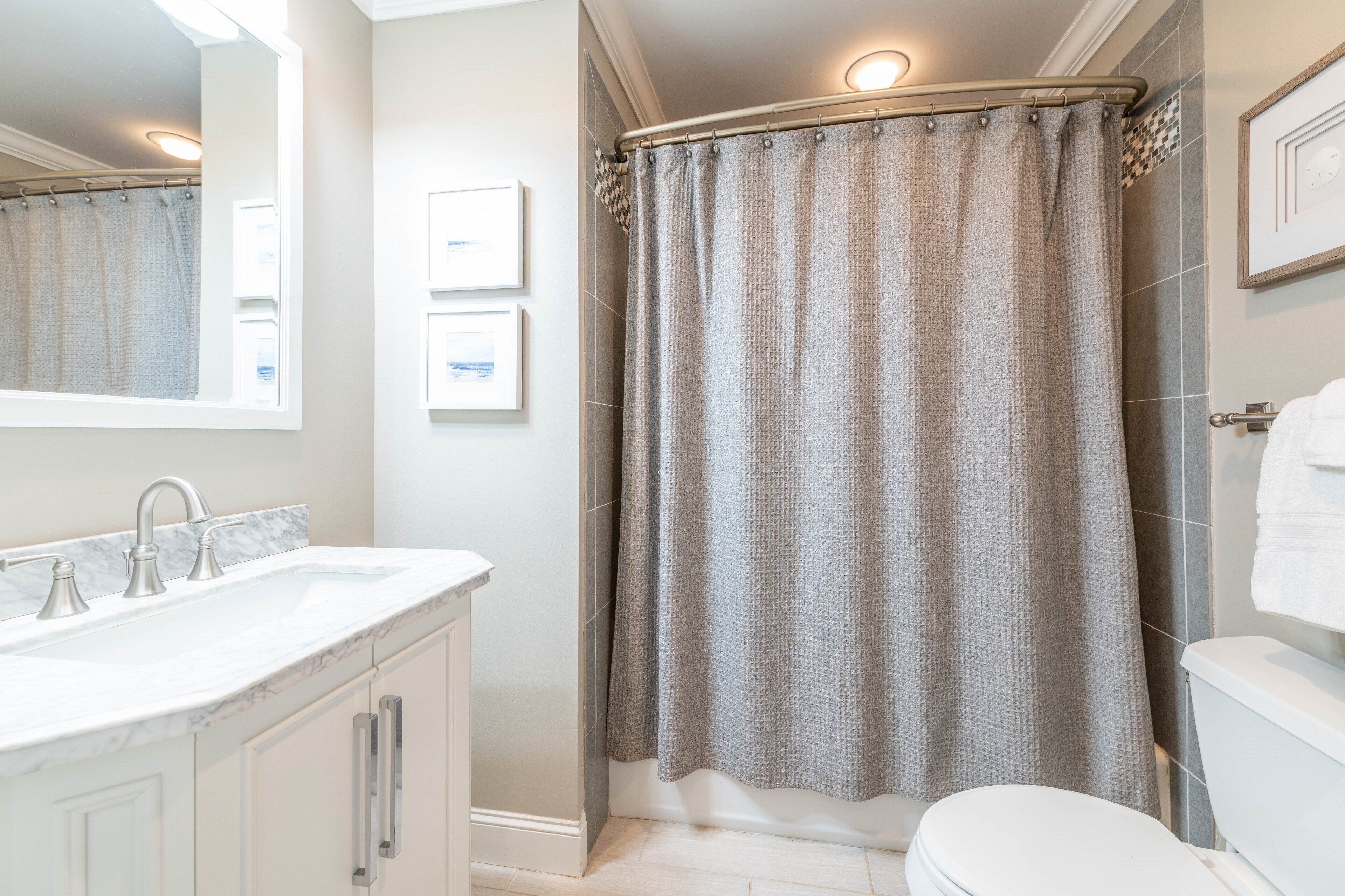A bathroom with a white sink, a toilet, and a shower curtain.
