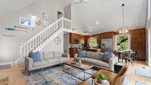 A spacious living area with a staircase, a kitchen, and a dining area.