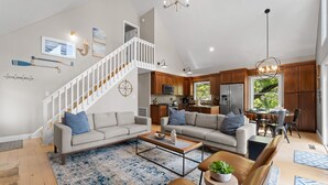 Un vaste salon avec un escalier, une cuisine et un coin repas.
