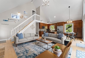 A spacious living room with a staircase, a kitchen, and a dining area. - Blarney Bay (Mooresville)