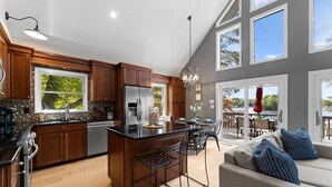 Une cuisine moderne avec des meubles en bois, un réfrigérateur en acier inoxydable et un grand îlot central doté de tabourets de bar.