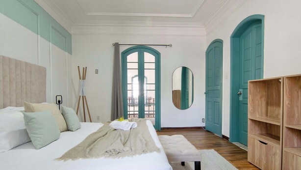 Ein Schlafzimmer mit einem großen Bett, einem Nachttisch, einem Spiegel und einem Kleiderschrank.