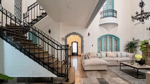 Ein großzügiger Wohnbereich mit Treppe, einem beigen Sofa und einem Couchtisch.