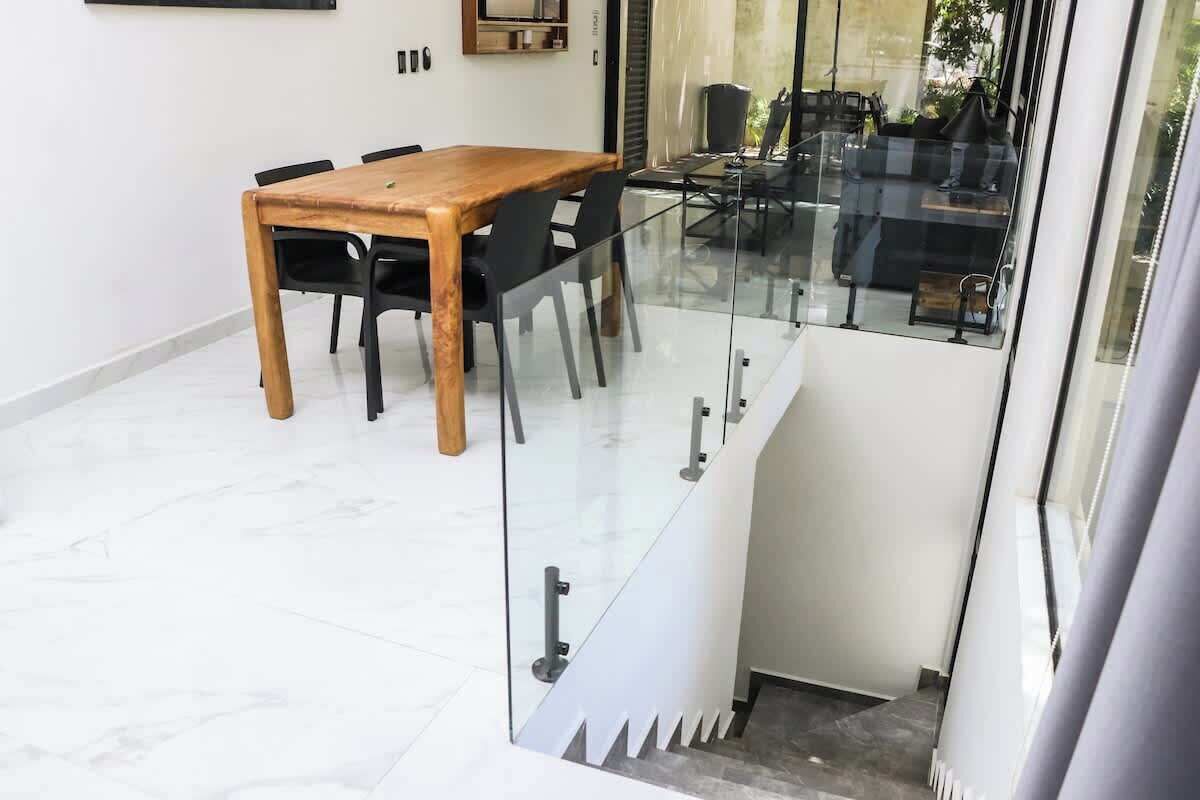 A modern dining area with a wooden table and black chairs, a glass partition, and a view of outdoor seating.