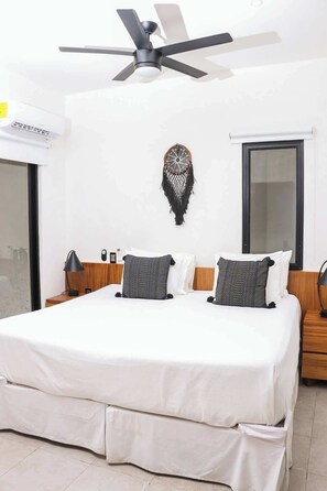 A modern bedroom with a large bed, a ceiling fan, and a decorative wall hanging. - Escapada de lujo en Playacar (Playa del Carmen)