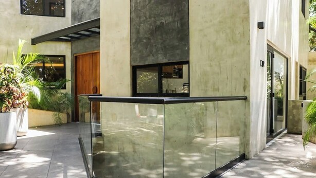 Un edificio moderno con fachada de vidrio, exterior de concreto y una pequeña puerta de madera.