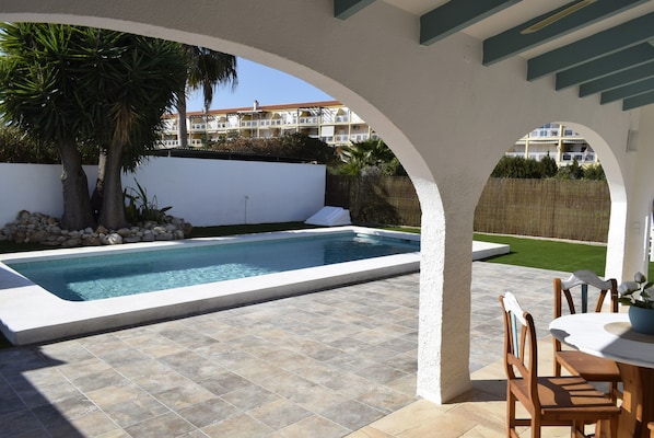 A swimming pool with a tiled deck, surrounded by a white wall and a wooden fence. - 04 Ch4400 in Denia With 4 Bedrooms and 4 Bathrooms (Denia)