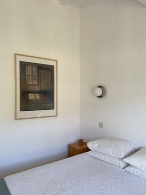 A bedroom with a bed, a nightstand, a framed picture, and a wall-mounted light fixture. - Country House on the Paiva River – Hostiva (Castro Daire)