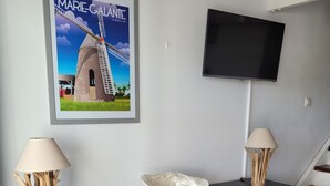 Un saló modern amb un moble de fusta, dues làmpades, un quadre amb un molí de vent i un televisor de pantalla plana penjat a la paret.