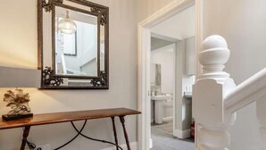 Un couloir avec un banc en bois, un miroir et un escalier.
