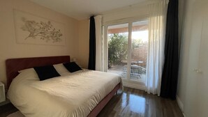 Ein Schlafzimmer mit Bett, Fenster und Blick ins Freie.