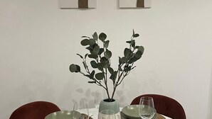 Ein runder Esstisch mit vier grünen Tellern, zwei Weingläsern und einer Vase mit einem Zweig.